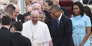 Der Papst, Michelle und Barack Obama lachen, umringt von Geistlichen
