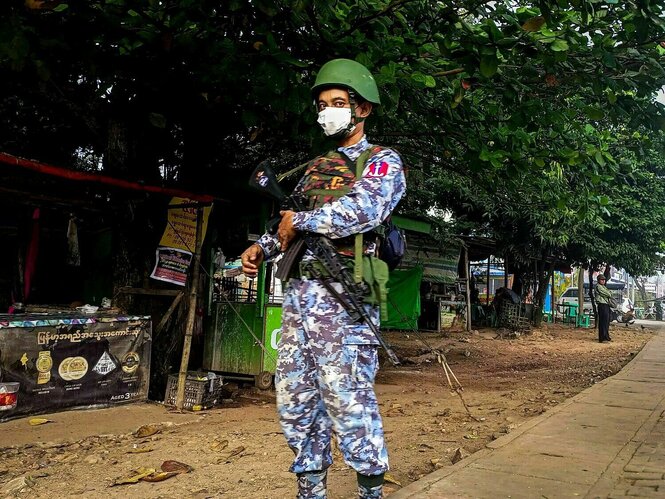 Ein einzelner Soldat steht vermummt auf der Straße in Yangon mit einem Maschinengewehr