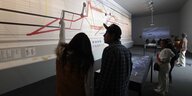 Ausstellungsansicht mit Grafiken von Forensic Architecture an der Wand