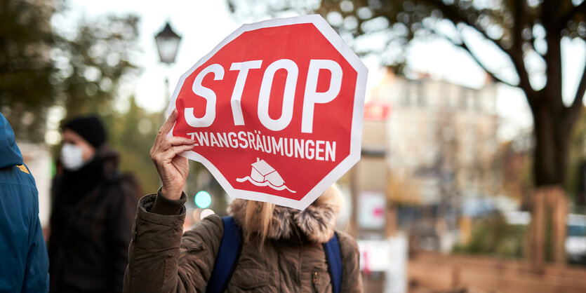 Eine Person hält ein Schild mit der Aufschrift "Zwangsräumung verhindern"