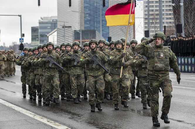 Deutsche Soldaten laufen in einer Gruppe mit einer Deutschland-Flagge durch eine Straße in Vilnius.