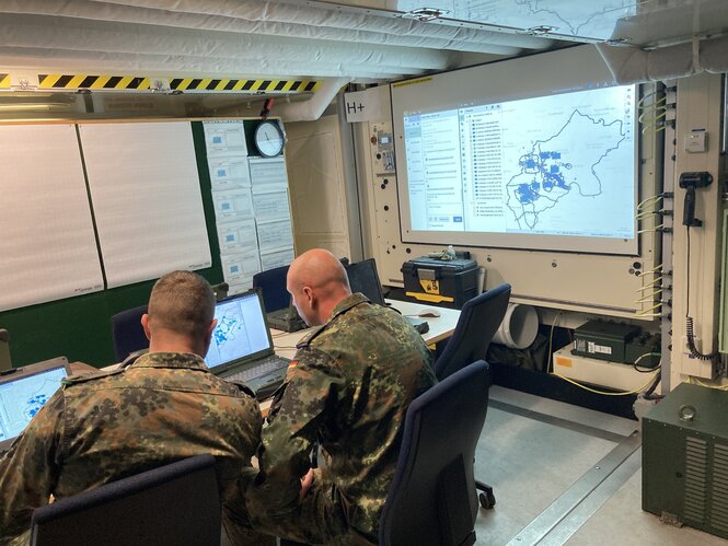 Zwei Soldaten in Uniformen schauen auf Computer.