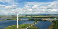 Windkraftanlagen drehen sich bei leichter Bewölkung in einem Solarpark. (Aufnahme mit Drohne)