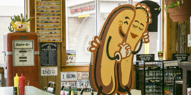 Ein Aufstellschild im Diner zeigt zwei Hotdog-Würstchen, die sich umarmen.