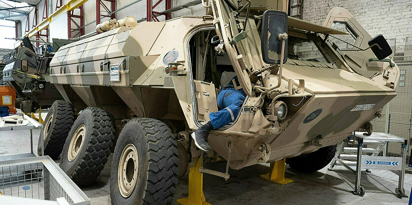 Ein Mitarbeiter von Rheinmetall arbeitet an einem Panzer vom Typ Fuchs.