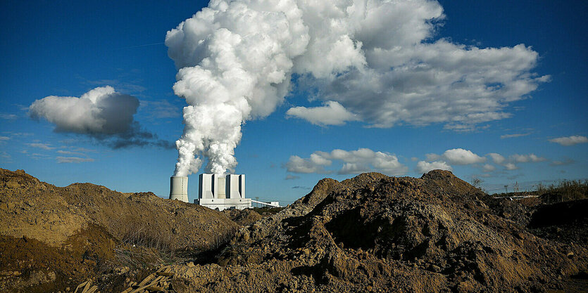 Das Braunkohlekraftwerk Lippendorf ist hinter Erdhügeln einer Ausgrabung zu sehen.