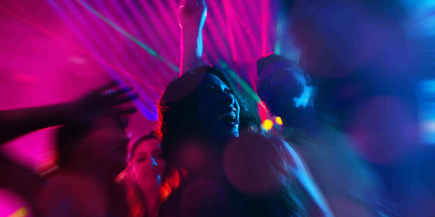 Verschiedene Personen tanzen im bunten Scheinwerferlicht.