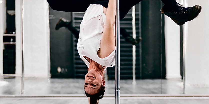 Nele Sehrt hängt kopfüber an einer Poledance-Stange