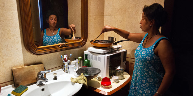 Eine Frau kocht Essen auf einem Elektroherd im Badezimmer