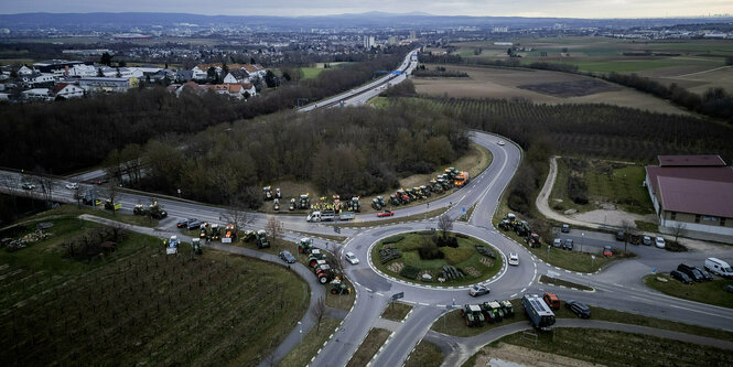 Landwirte stehen mit ihren Traktoren an einem Kreisel