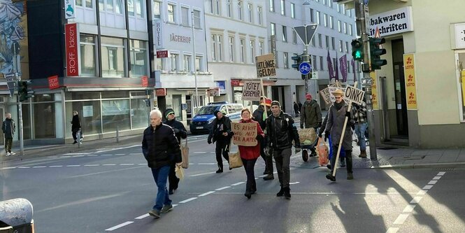 Eine kleine Gruppe von Menschen geht mit Protestschildern über die Straße - auf den Schildern stehen Forderungen wie: Tötet Özdemir, Oink!, Es reicht weg mit der Ampel...