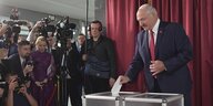Alexander Lukaschenkowirft einen Wahlzettel in eine Wahlurne während er fotografiert wird
