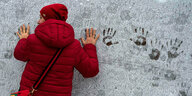 Eine Frau hinterlässt Handabdrücke auf einer mit Frost bedeckten Mauer in St. Petersburg