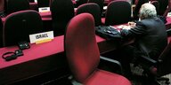 Ein leerer Stuhl in einem Konferenzsaal, davor ein Schild mit der Aufschrift "Israel".