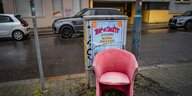 Ein rosafarbener Sessel auf einer regennassen Straße