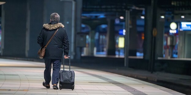 Ein Mann mit einem Koffer am hamburger Hauptbahnhof, er trägt eine warme Winterjacke