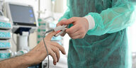 Ein Pfleger legt in einem Krankenzimmer bei einem Patienten ein Messgerät an