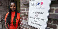 Eine Frau steht neben einem Schild: Landesamt für Zuwanderung und Flüchtlinge