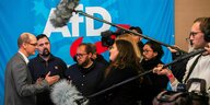 Journalisten und Journalistinnen diskutieren mit Stefan Moeller, Co-Landessprecher der AfD, (links) und halten ihm ihre Mikrofone entgegen