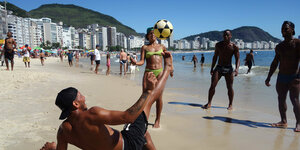 Mehrere Personen spielen Fußball an einem Strand.