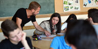 Ein Lehrer hilft einer Schülerim im Deutschunterricht.