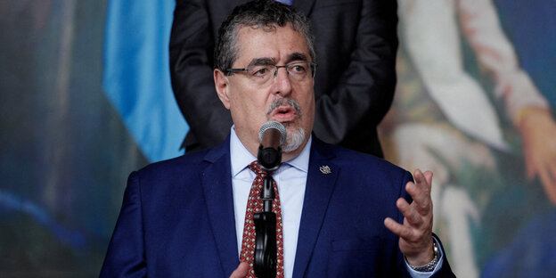 Ein Mann im dunkelblauen Anzug, Bernardo Avelaro, steht am Mikrofon