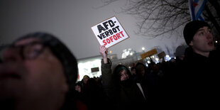 Kundgebung in der Nacht im Berliner Regierungsviertel, ein Demonstrant hält ein Schild in den Abendhimmel: AFD-Verbot sofort