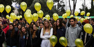 Eine Ansammlung junger Menschen mit gelben Luftballons