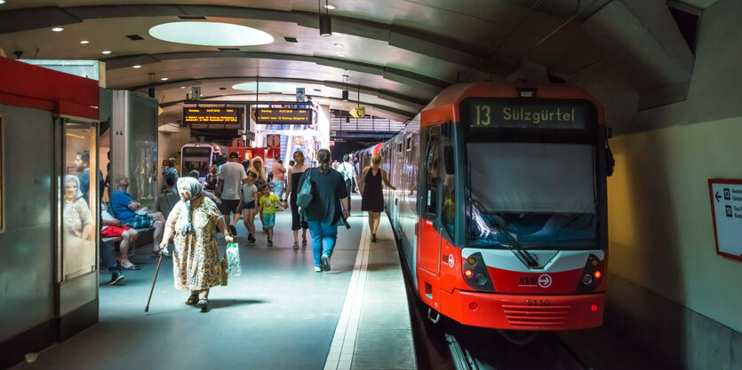 Untergrundhaltestelle einer Straßenbahn, mehrere Menschen auf dem Bahnsteig. Auf der Bahnlinie 13 der Kölner Verkehrsbetriebe AG steht die Endhaltestelle "Sülzgürtel".