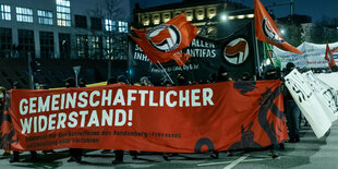 Demonstranten gehen hinter einem großen Transparent mit der Aufschrift «Gemeinschaftlicher Widerstand! - Solidarität mit den Betroffenen des Rondenbarg-Prozesses und Einstellung aller Verfahren» durch die Hamburg. Die Protestierenden sind schwarz gekleidet und vermummt, viele Antifa-Fahnen wehen. Sie protestieren gegen den ersten Gruppenprozess wegen schweren Landfriedensbruchs im Zusammenhang mit den Krawallen rund um den g20-Gipfel im Jahr 2017 . Das Bild ist von einer Demo am 5. Dezember 2020.