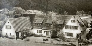 Eine alte Postkarte zeigt ein Gebäudekomplex in einer hügeligen Wald- und Wiesenlandschaft