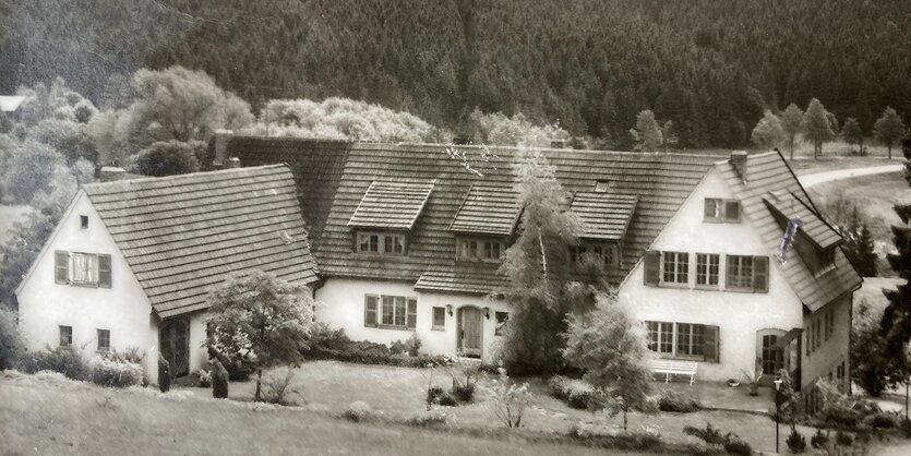 Eine alte Postkarte zeigt ein Gebäudekomplex in einer hügeligen Wald- und Wiesenlandschaft