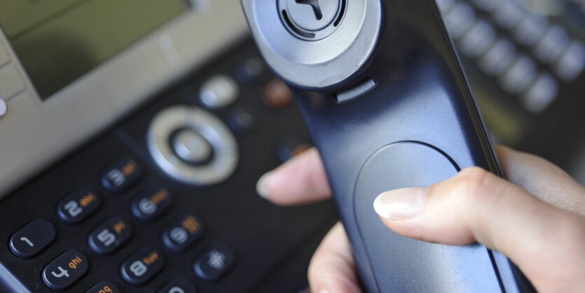 Eine Frau hält einen Telefonhörer in der Hand.