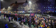 Eine Menschenmenge im Schnee versammelt sich vor beleuchteten Gebäuden
