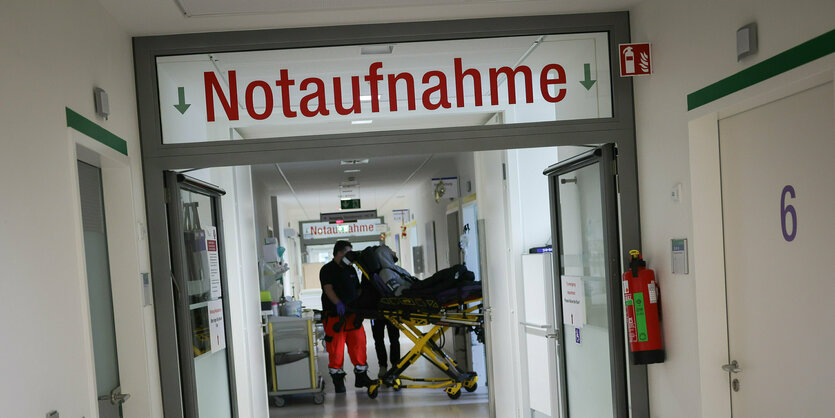 Ein Patient auf einer Bahre wird von Sanitätern in die Notaufnahme geschoben