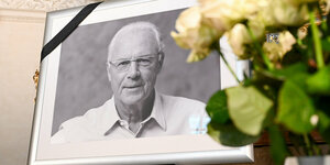 gerahmtes Foto von Franz Beckenbauer mit Trauerflor und Blumen daneben