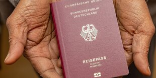 Eine Person hält einen deutschen Reisepass in den Händen.