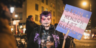 Tätowierte Demonstrantin mit lila Haaren und einem Plakat "Kein Mensch ist illegal"