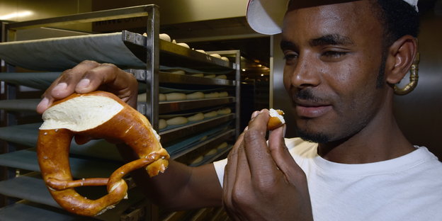 Bäckerlehrling Ghebru Aregay aus Eritrea probiert eine Brezel
