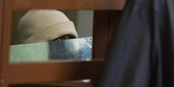 Ein Angeklagter versteckt sein Gesicht hinter einer Mappe, zu Prozessbeginn wegen einer mutmaßlichen Vergewaltigung im Görlitzer Park vor dem Kriminalgericht Moabit in Berlin