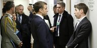 Der französische Präsident Emmanuel Macron spricht mit dem CEO von OpenAI, Sam Altman R der an der Wand lehnt