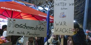 Menschen halten Schilder bei einer Demo hoch