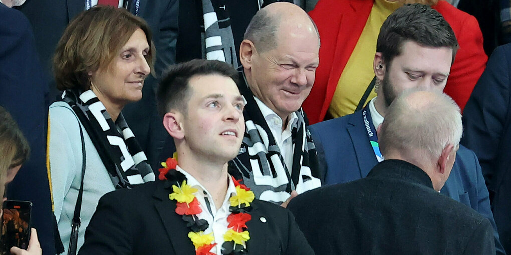 Olaf Scholz steht mit anderen auf der Tribüne