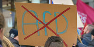 Ein durchgestrichenes AfD-Logo ist auf einem Schild bei einer Demo gegen Rechts zu sehen.