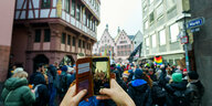 Ein Mensch macht mit seinem Smartphone eine Aufnahme von der überfüllten Demo in Frankfurt