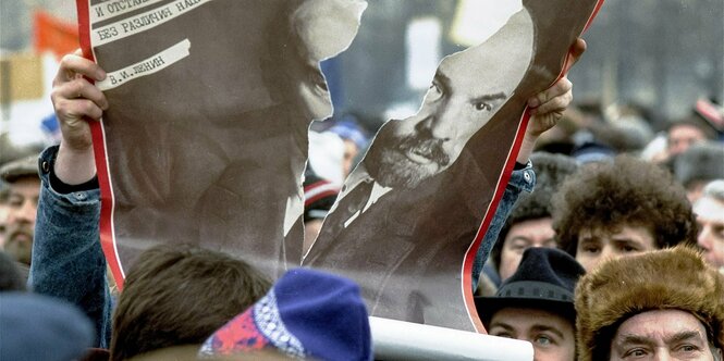 Ein Demonstrant zerreißt ein Lenin-Plakat auf einer Demo in Moskau 1990