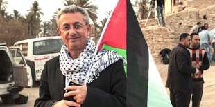 Mustafa Barghouti hat ein Palli-Tuch um den Hals gebunden und erträgt eine Palästinenser-Fahne