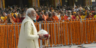 Der festlich gekleidete Premier Modi auf dem Weg zur Tempeleröffnung - Hindus stehen hinter einer Absperrung und beobachten ihn dabei