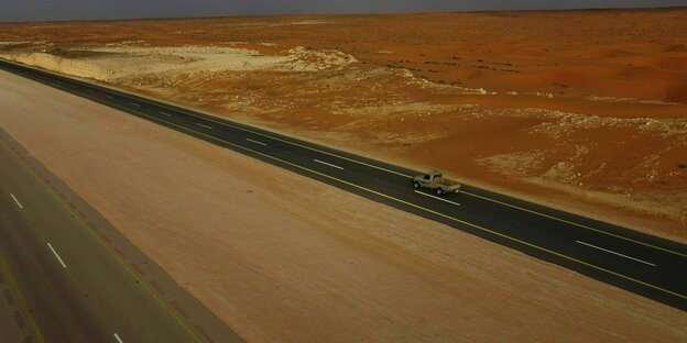 Geteerte Strasse durch die Wüste Saudi Arabiens auf derein einsamer Transporter unterwegs ist