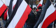 Personen tragen schwarz-weiß-rote Fahnen bei einer Demonstration